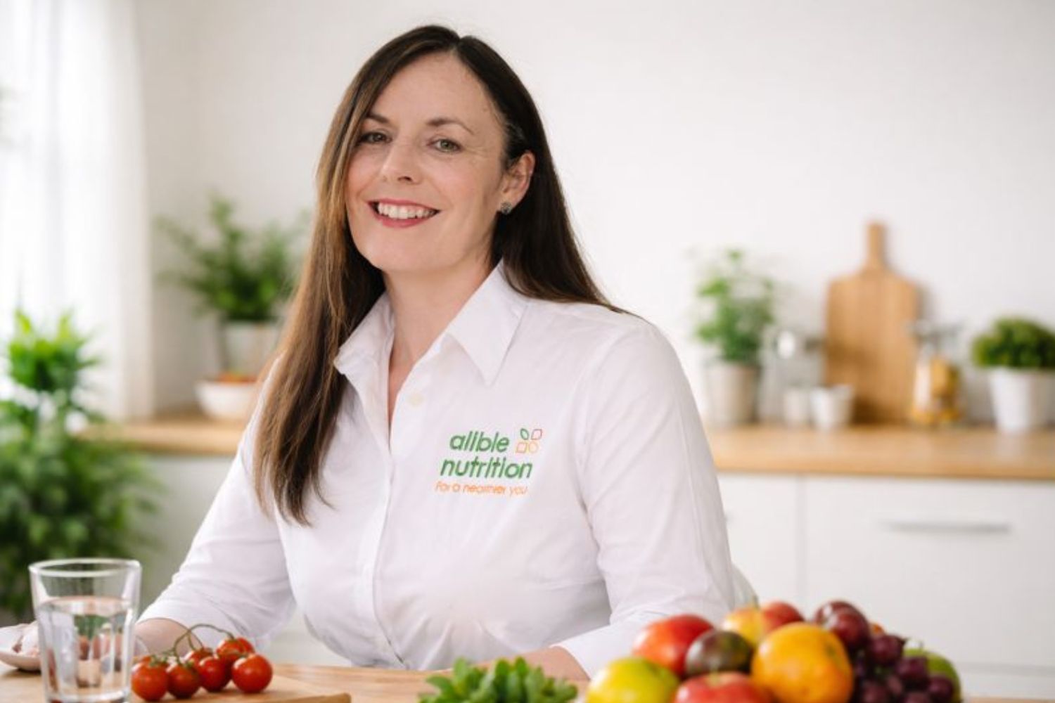 Photo of me in branded shirt sitting in a light-coloured kitchen