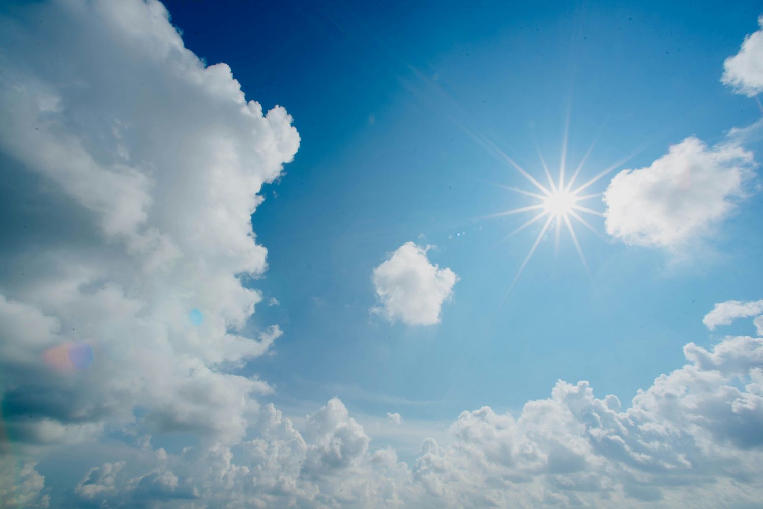 Blue sky with white clouds and a small sun